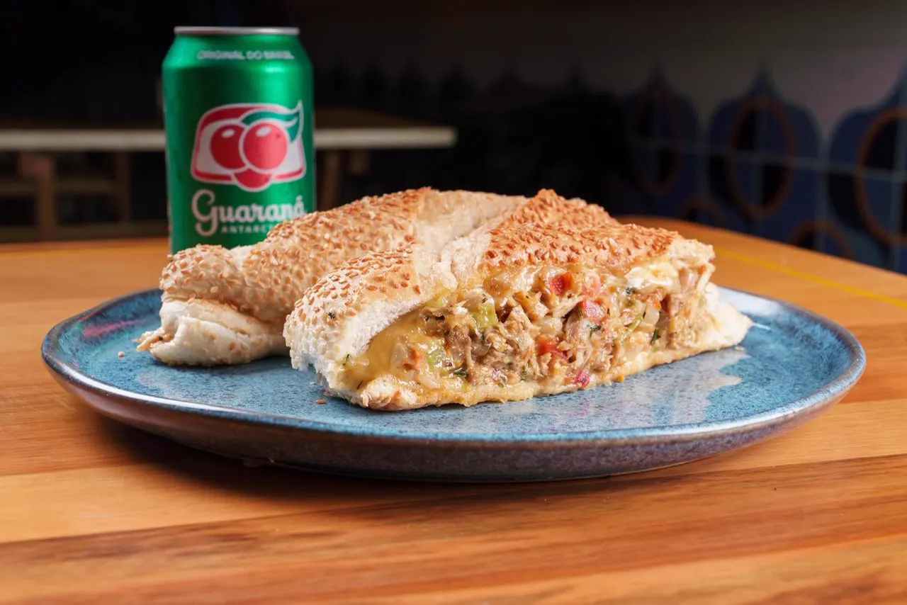 Lanche de pernil desfiado com queijo derretido, no pão francês com gergelim