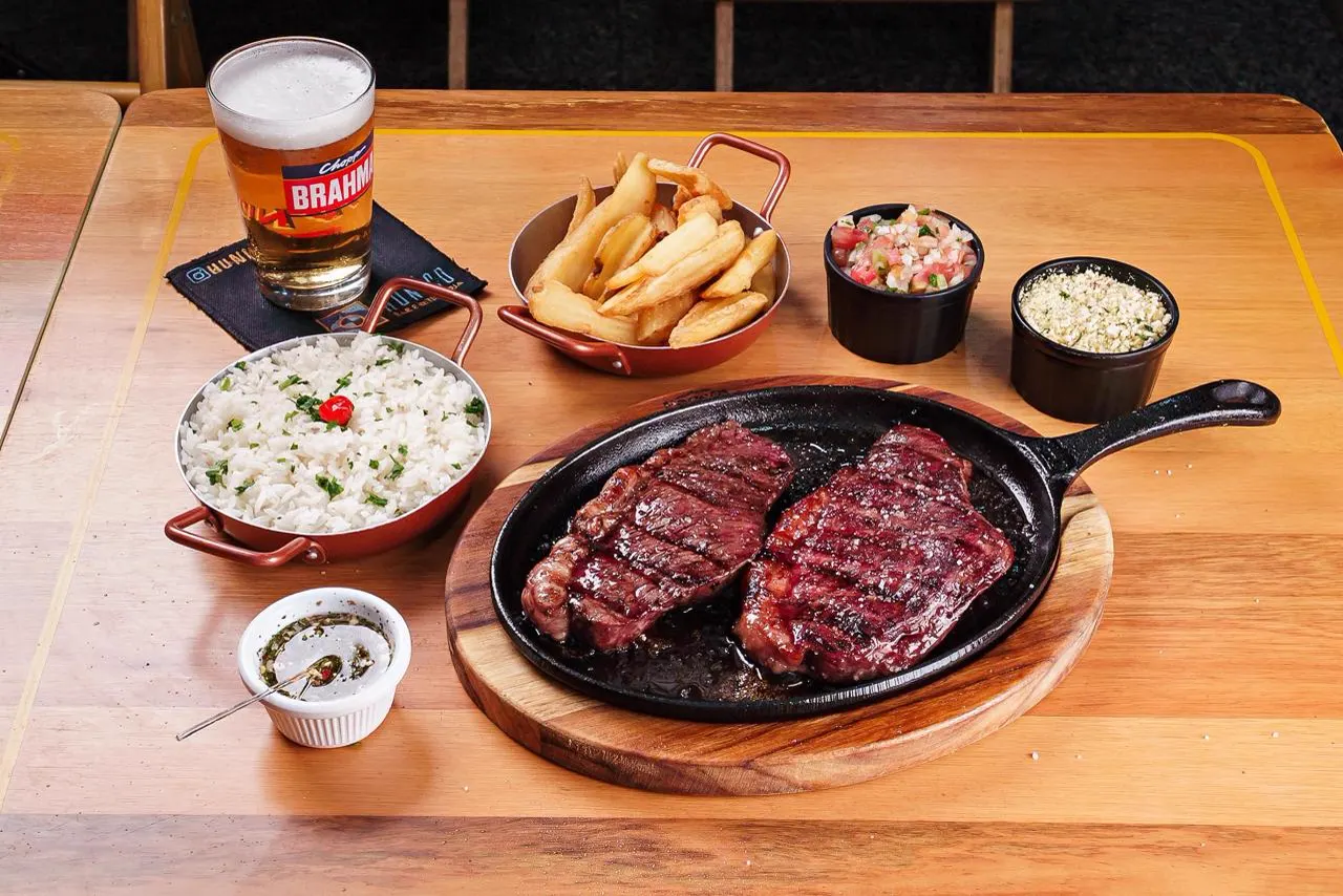 Picanha na chapa de ferro sobre tábua, com arroz, mandioca frita, vinagrete, farofa e chopp Brahma