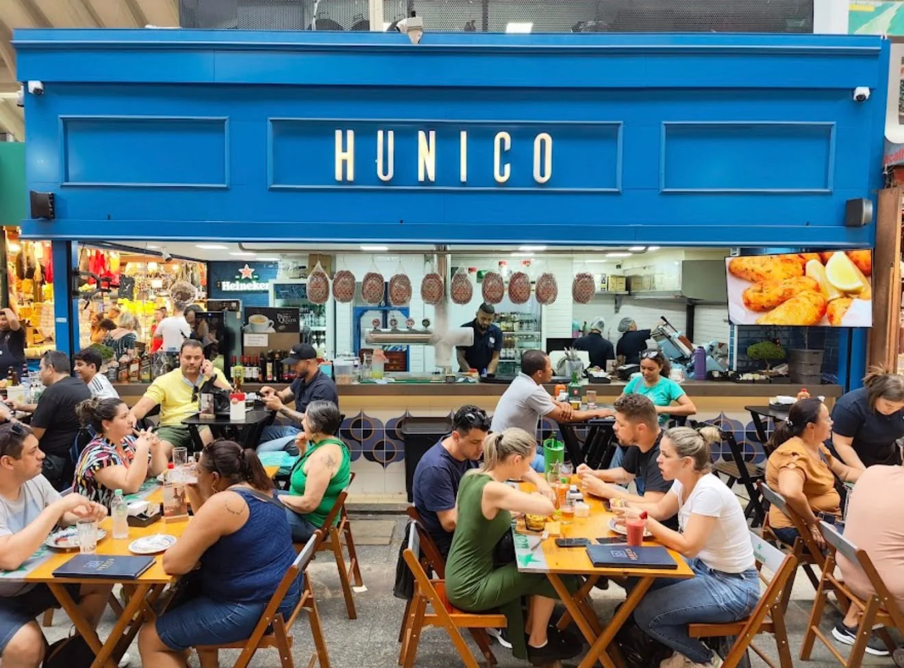 Fachada azul e mesas do Hunico no Mercado Municipal de São Paulo