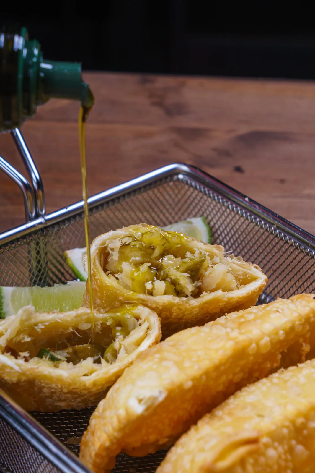 Pastel de bacalhau aberto recebendo um fio de azeite