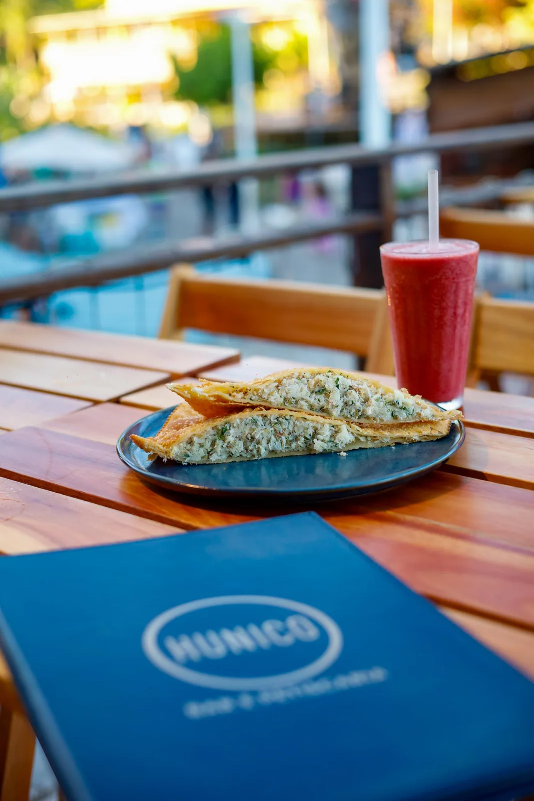 Pastel de bacalhau aberto no prato azul, com suco ao lado