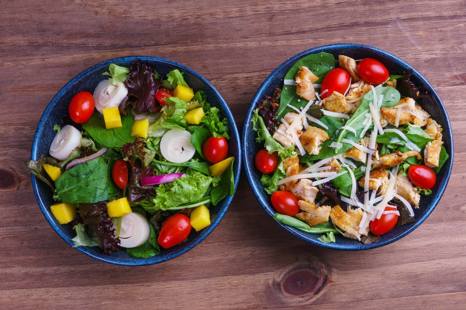 Salada tropical e salada de frango servidas em pratos azuis