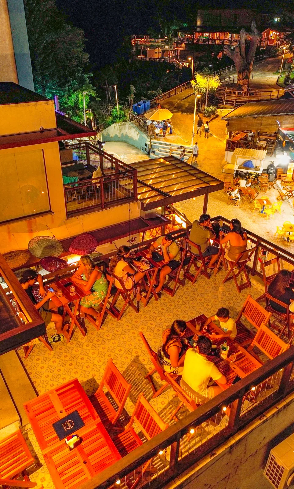Mesas da varanda do Hunico Morro com vista para a praça à noite